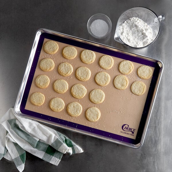 A baking sheet with Choice purple silicone baking mat with cookies on it.