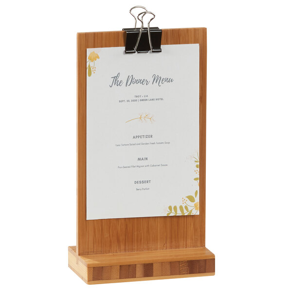 A Cal-Mil bamboo clipboard menu holder on a table with a menu.