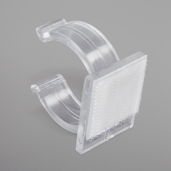 A close-up of a clear plastic Snap Drape table skirt clip with a hook and loop attachment.