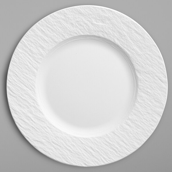 A white porcelain coupe plate with a textured edge.