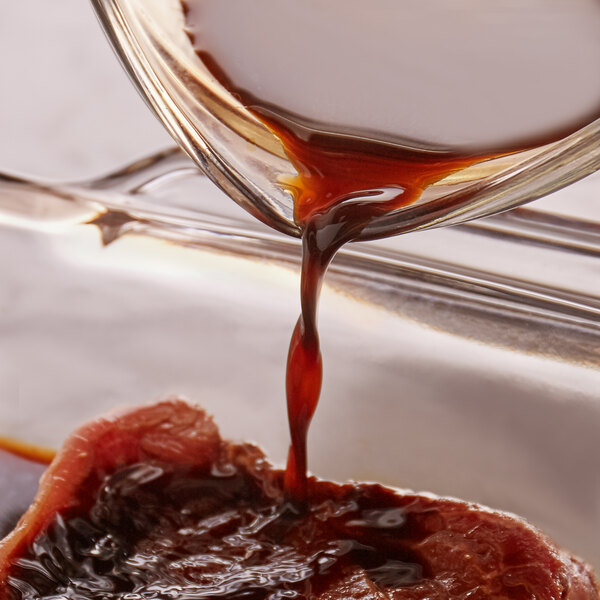 A close-up of French's Worcestershire Sauce being poured onto a steak.