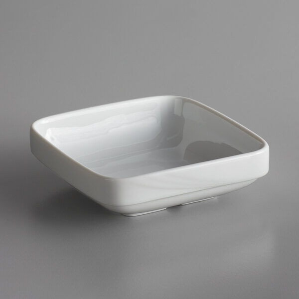 A Schonwald white porcelain square bowl on a gray surface.
