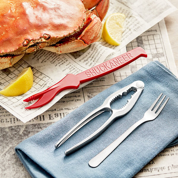A crab with a Choice Cocktail Seafood Sheller and Oyster Fork on a newspaper.