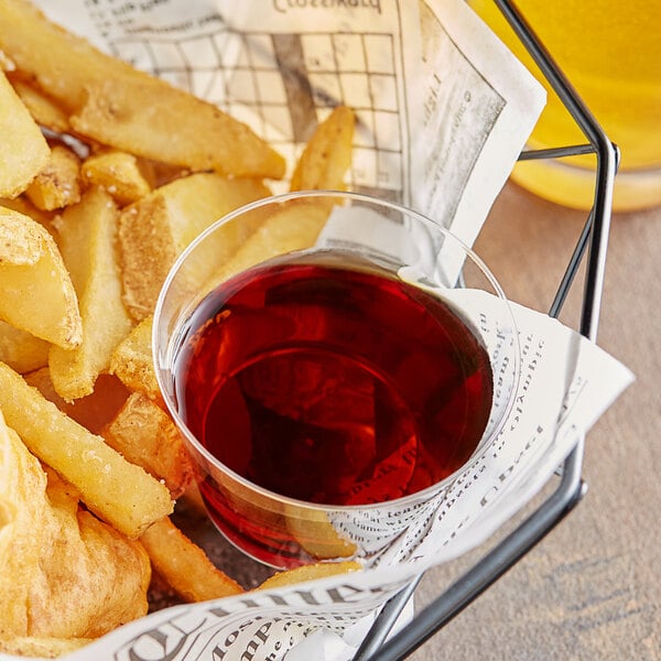 A basket of french fries with a glass of Heinz English style malt vinegar on a table.