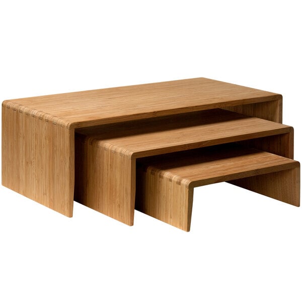 A bamboo 3-piece cascade riser set on a table with sushi.