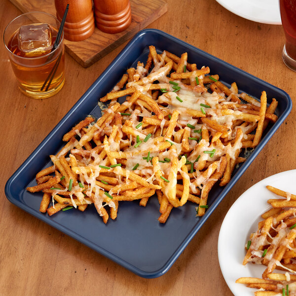 A Baker's Mark dark blue aluminum sheet pan with french fries topped with cheese and chives on it.