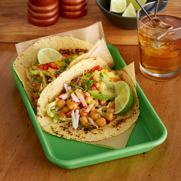 A Baker's Mark green wire in rim aluminum tray with tacos and a drink.