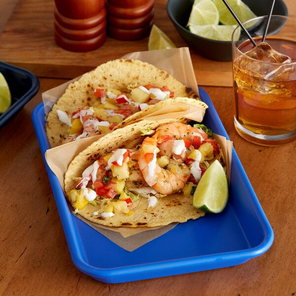 A Baker's Mark light blue aluminum tray with shrimp tacos and a drink on a table.