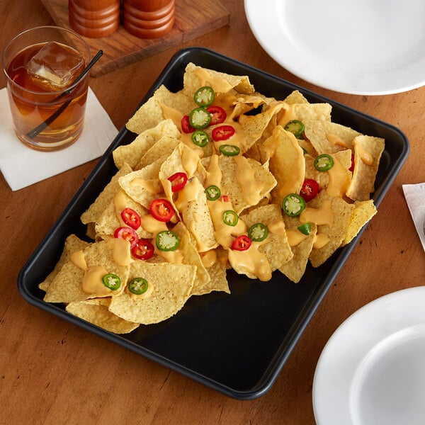 A Baker's Mark black non-stick aluminum sheet tray with nachos topped with jalapenos and cheese.