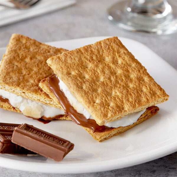 A plate with two s'mores made with Nabisco Original Graham Crackers, chocolate, and marshmallows.