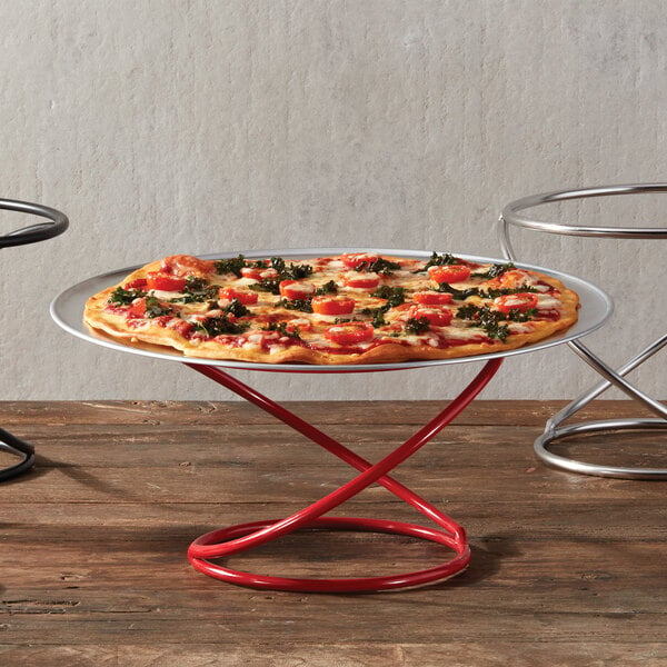 An American Metalcraft red wrought iron swirl display stand with a pizza on it.