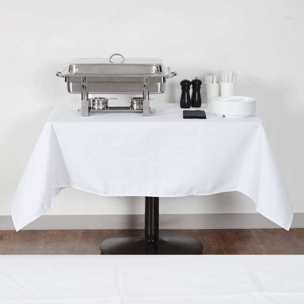 A rectangular white table with a white tablecloth on it.