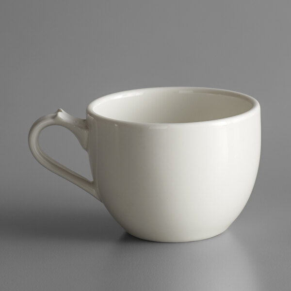 A white RAK Porcelain coffee cup with a handle on a gray surface.