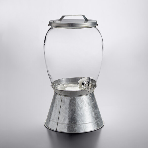 A Stylesetter glass beverage dispenser with a metal lid.