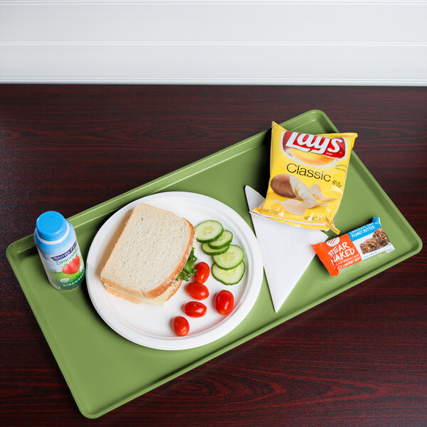 A green Cambro dietary tray with a sandwich, vegetables, and a drink.
