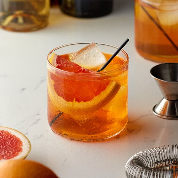 A glass of Monin Winter Citrus drink with ice and orange slices.