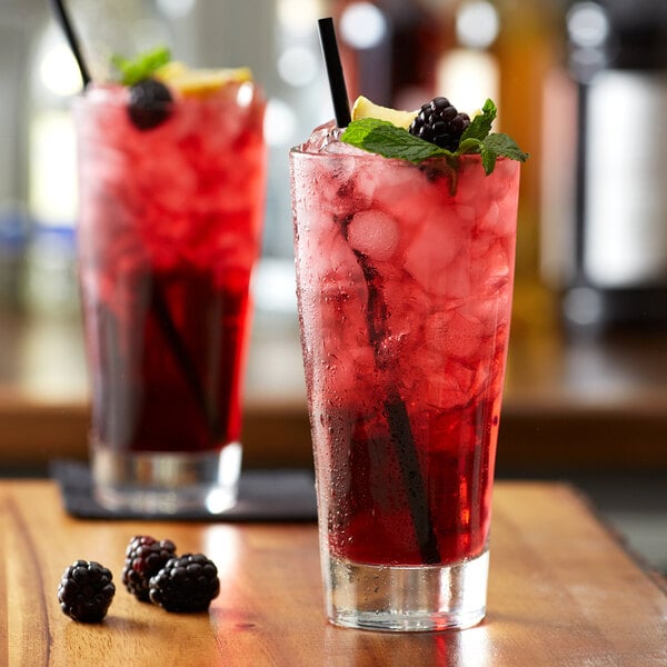 A glass of red Monin Sugar Free blackberry syrup with ice.