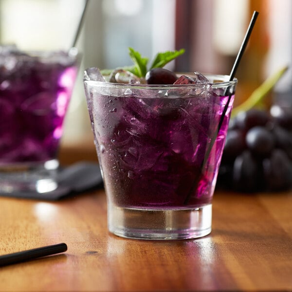 A glass of Monin Wild Grape syrup with ice and a purple drink garnish.