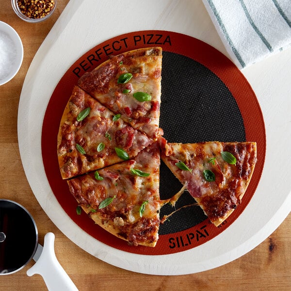 A round pizza on a Sasa Demarle SILPAT baking mat with a slice missing.