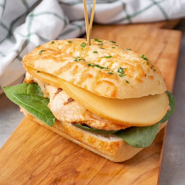 A sandwich with cheese and chicken on a cutting board.