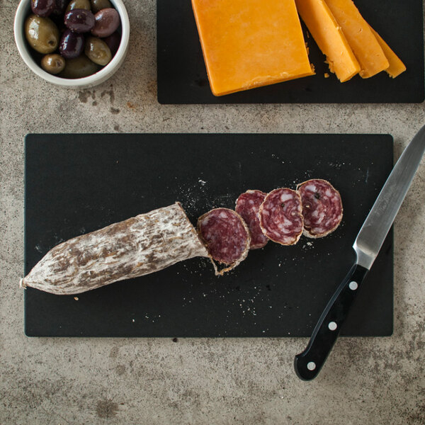 An Epicurean Richlite wood fiber cutting board with sliced sausage, cheese, and olives.