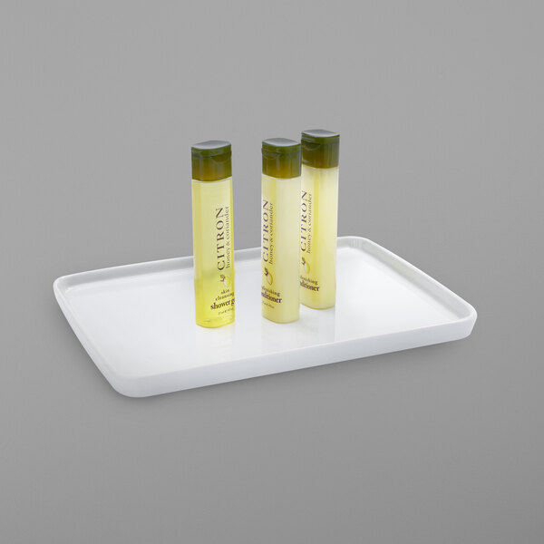 A white ceramic amenity tray holding three bottles of shampoo and conditioner.
