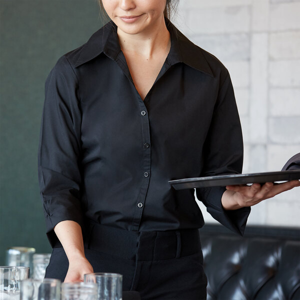 A woman wearing a black Henry Segal V-neck dress shirt holding a tray and a glass of water.