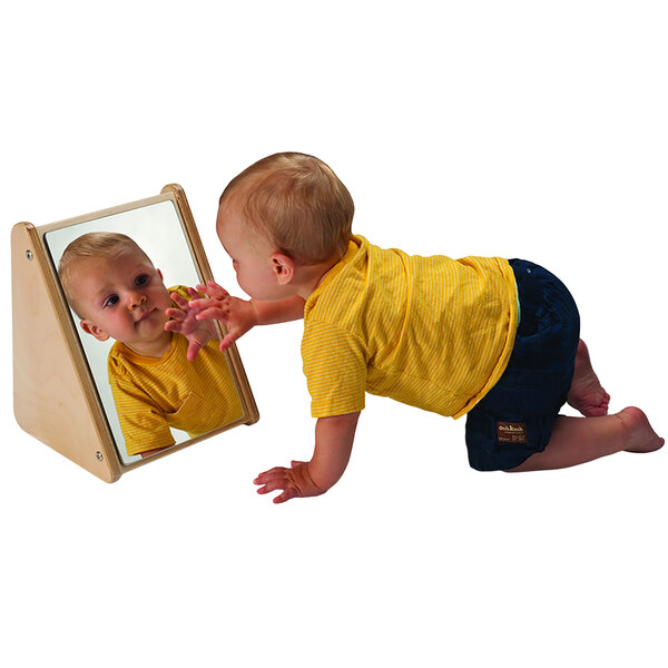 A baby looking at themselves in a Whitney Brothers infant mirror stand.