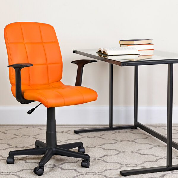 An orange Flash Furniture office chair with arms sits next to a glass desk.