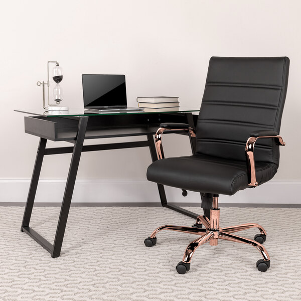 A Flash Furniture black leather office chair with rose gold arms and base next to a glass desk with a laptop.