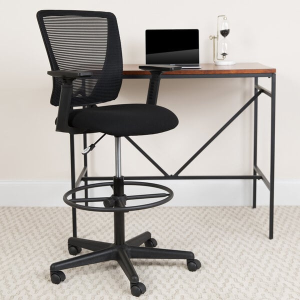 A Flash Furniture black mesh drafting chair with a laptop on it.