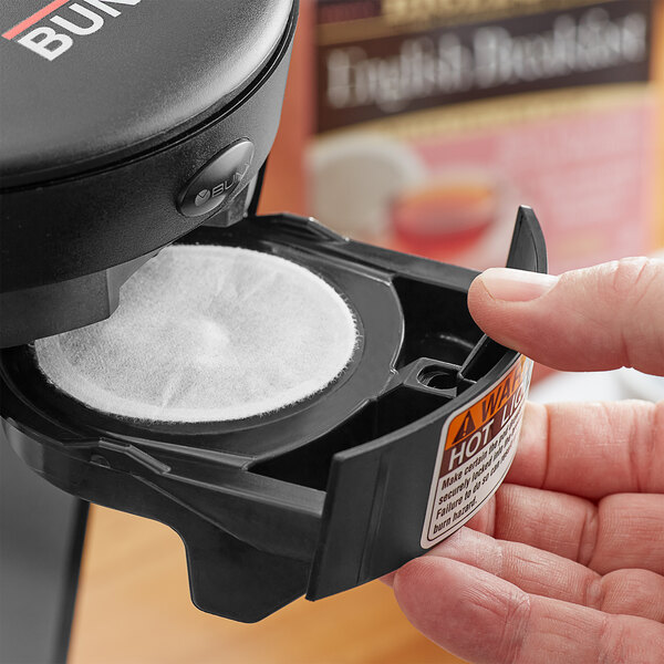 A hand holding a black Bigelow English Breakfast Tea single serve container.