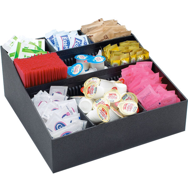 A black Cal-Mil coffee condiment organizer on a counter filled with condiments.