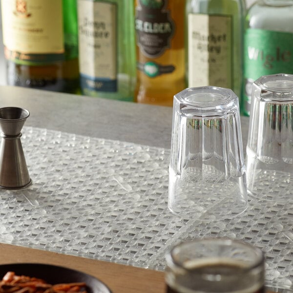 A Choice clear interlocking bar mat on a counter with two glasses and a bottle of liquor.