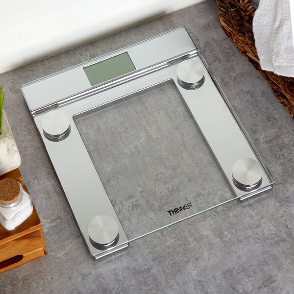 A Conair Thinner digital glass scale on a grey surface.