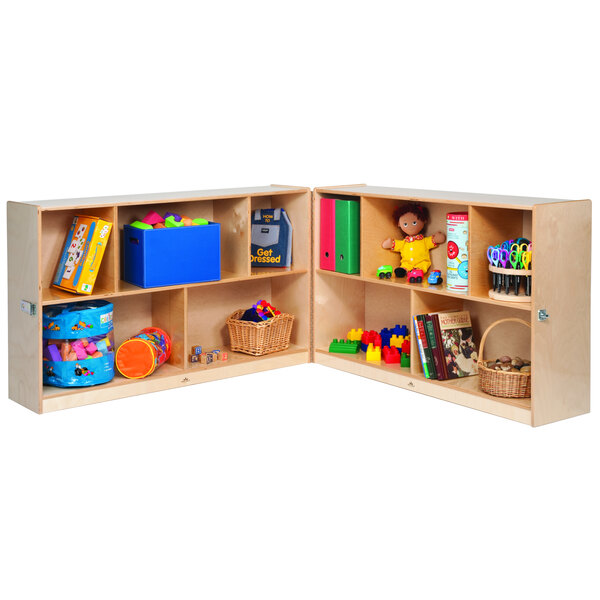 A Whitney Brothers wooden storage cabinet with ten compartments holding toys and books.
