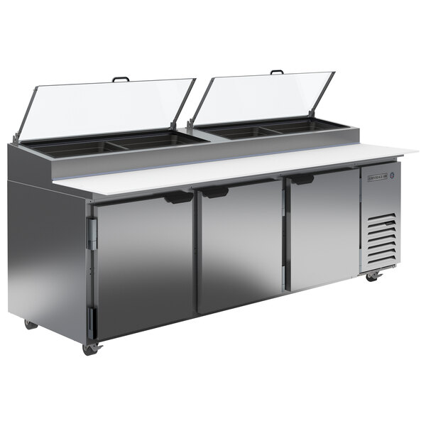 A Beverage-Air stainless steel refrigerated pizza prep table with three clear lids.
