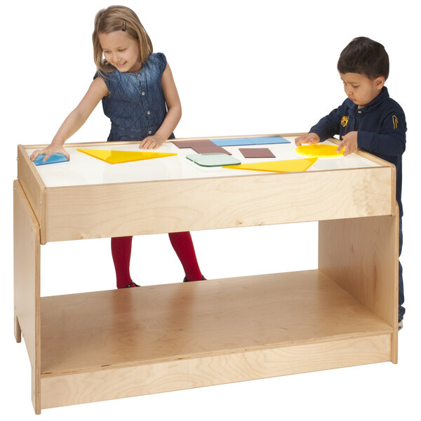 Two children playing with a Whitney Brothers rectangular wood table with a light box on top.