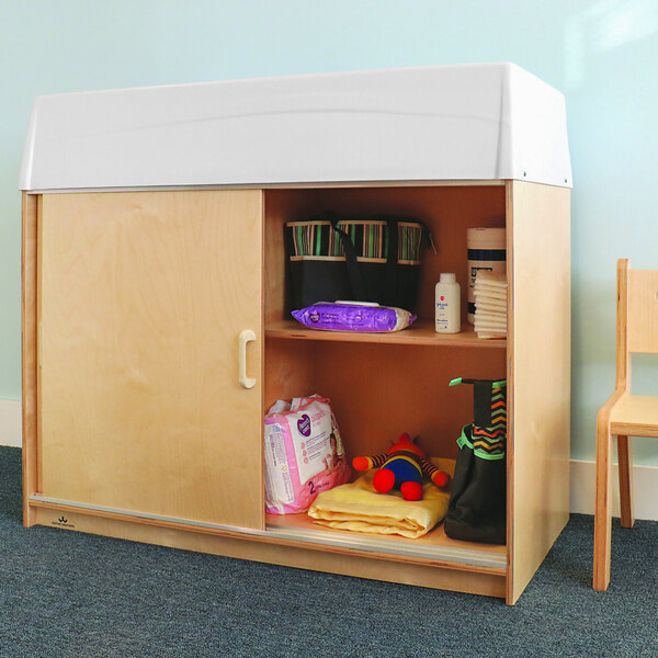 A Whitney Brothers wooden cabinet with a white top and a diaper changing table.