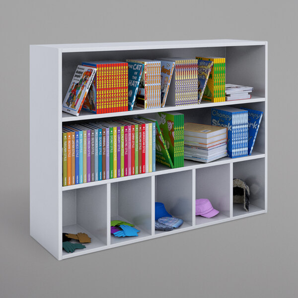 A Whitney White melamine cabinet with 5 cubbies and 2 shelves holding books and a variety of objects.