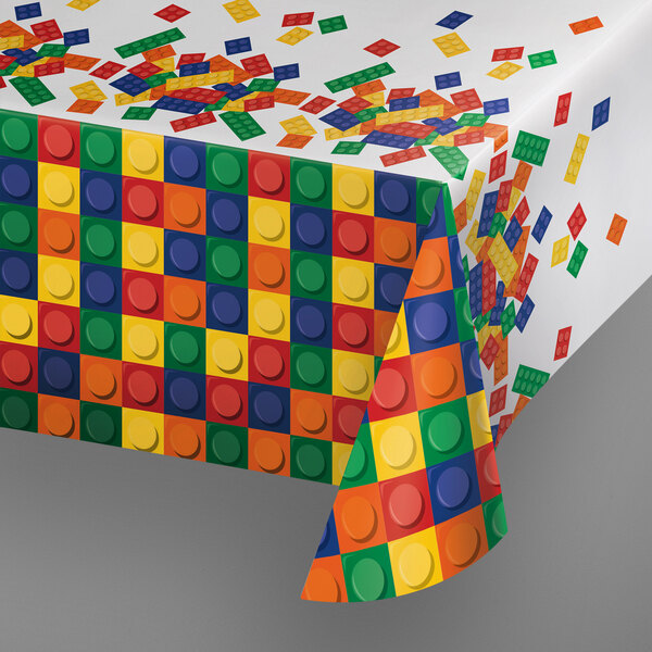 A Creative Converting Block Party plastic tablecloth on a table with colorful Lego blocks.