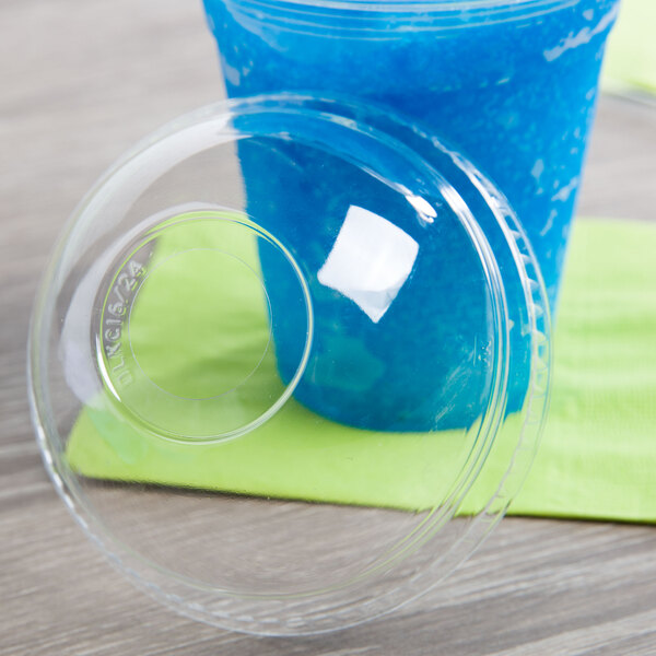 A plastic cup with a Fabri-Kal clear plastic lid and a blue drink on a table.