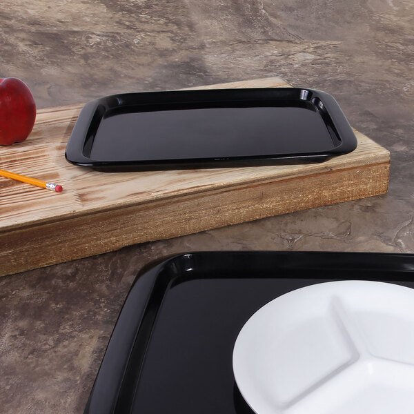 A black rectangular bamboo tray with a white plate on it.