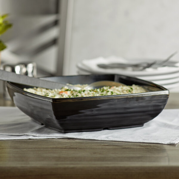 A black rectangular melamine bowl with food in it.