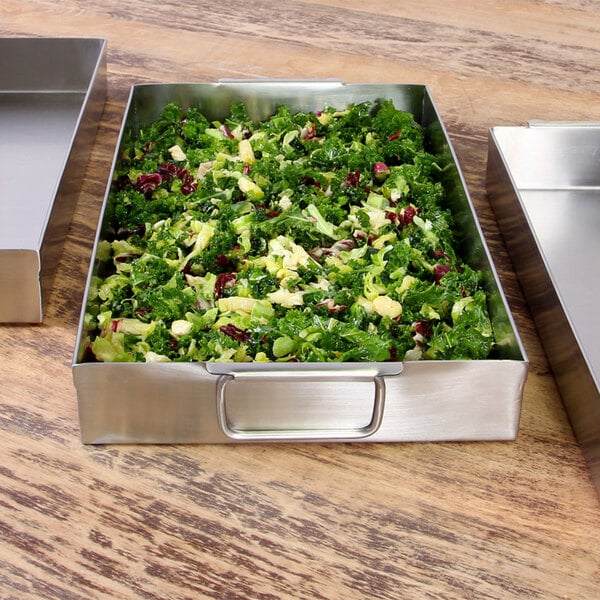 A metal tray with a salad in a metal pan.
