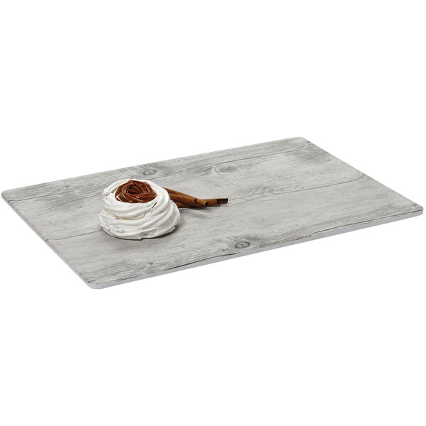 A white swirly dessert on a GET Madison Avenue faux white birch wood display board.
