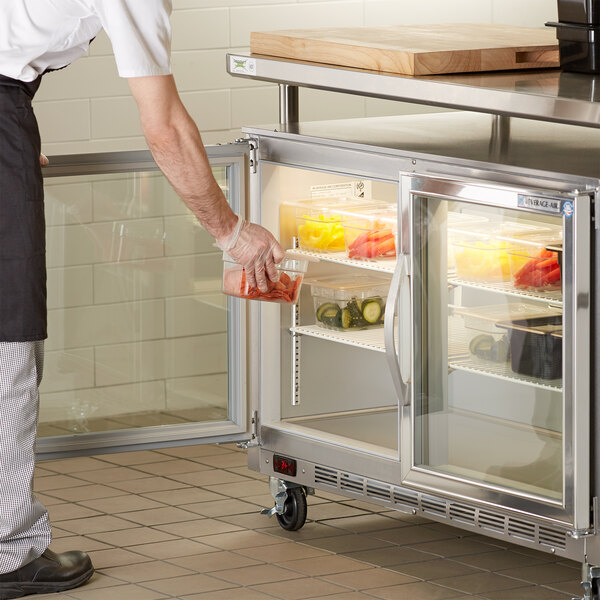 A man putting food into a Beverage-Air undercounter refrigerator.