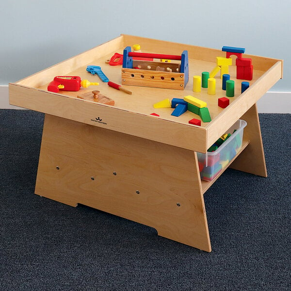 A Whitney Brothers toddler's wooden discovery table with toys on it.