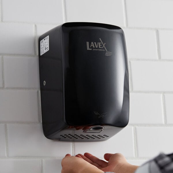 A person using a black Lavex stainless steel automatic hand dryer on a white wall.