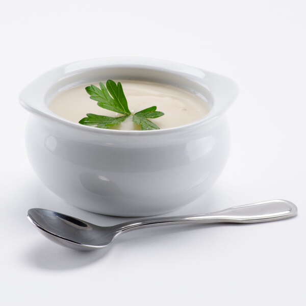 A bowl of Silver Skillet Cream of Mushroom Soup with a spoon and a green leaf.